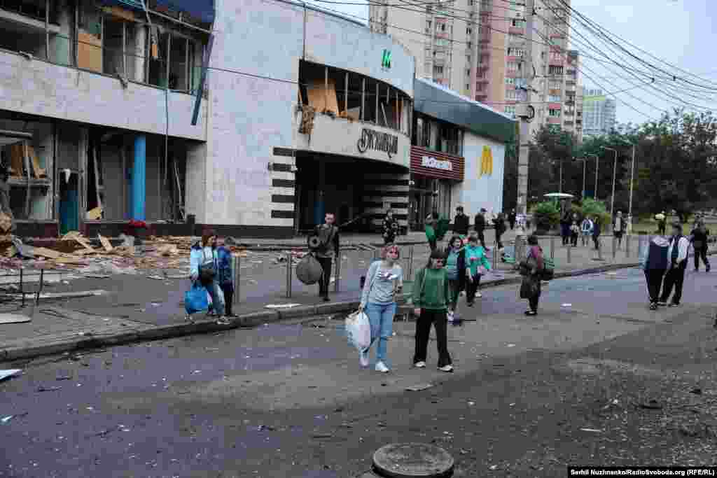 Люди залишають станцію метро «Лук'янівська», в якій переховувалися під час повітряної атаки РФ на Київ. Будівля метро пошкоджена цим та іншими російськими обстрілами
