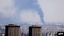 Iran- Smoke billows in the distance from an oil refinery following an Israeli strike on Tehran on June 17, 2025.