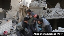 Сирійці рятують дитину після авіаудару в місті Хамурія, що в Східній Гуті, 21 лютого 2018 року