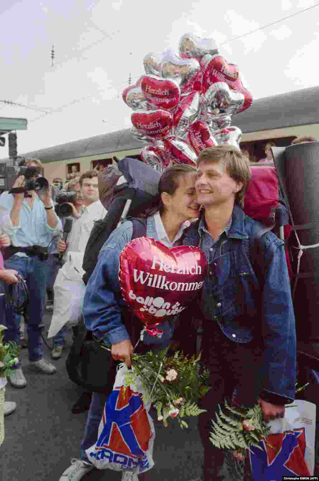 A smiling couple holds a balloon reading &quot;Warm Welcome&quot; in Passau, Germany, after riding by train from Lake Balaton, Hungary.&nbsp; &nbsp;