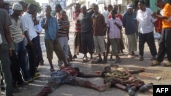 Жители сомалийского города Могадишо стоят возле тел двух погибших горожан. Иллюстративное фото.       