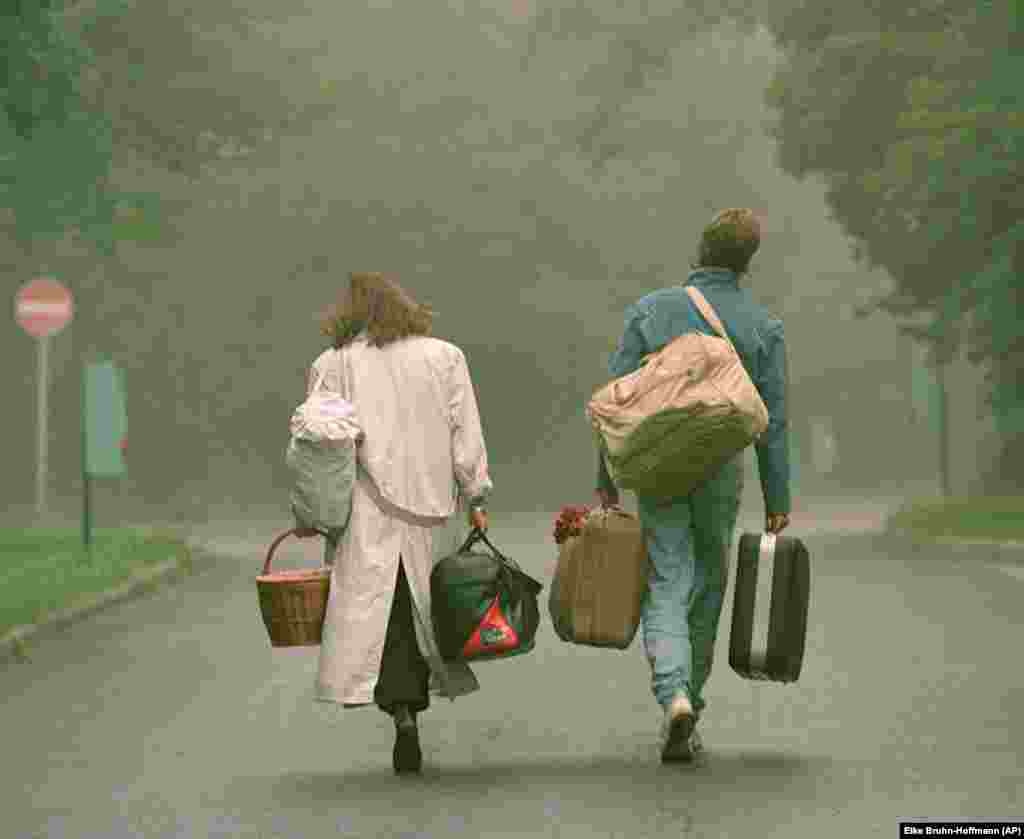 An East German couple walks near the&nbsp;Csilleberc refugee camp outside Budapest on September 4. More than 1,000 East German citizens were housed at the camp as they waited to make the trip to West Germany.