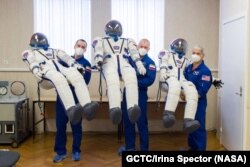 «Союз МС-18» космостук кемесинин экипажынын мүчөлөрү – “Роскосмос” агенттигинин космонавттары Олег Новицкий (командир) менен Пётр Дубров (учкуч) жана НАСАнын астронавты Марк Ванде Хай (Mark Vande Hei) өздөрүнүн скафандрларынын жанында. 2021-жылдын апрелинин башы.