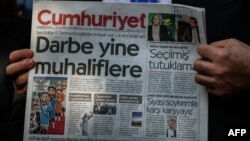 Мужчина держит в руках номер турецкой газеты Cumhuriyet. 