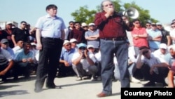 Театр режиссері Болат Атабаев (оң жақта) және "Рух пен тіл" ұйымының жетекшісі Жанболат Мамай (сол жақта) мұнайшылармен 2011 жылы жазда кездесіп тұр.  (Маңғыстау мұнайшылары ереуіліне арналған көрмедегі суреттің фотокөшірмесі). 