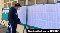 Шайлоо тилкесиндеги маалымат тактасынан тизме окуп турган жаран. Бишкек, 11-апрель, 2021-жыл. 
