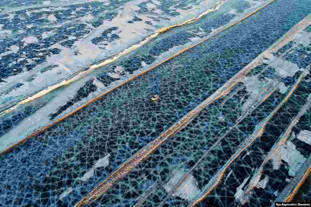 Машина на покрытой льдом поверхности реки Енисей. Это дорога, которая в зимнее время соединяет берега водоема на юге Красноярска.