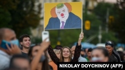 Участница антиправительственной демонстрации в Софии несет портрет премьер-министра Бойко Борисова в виде клоуна