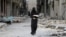 Syria -- A woman carries bread through a damaged street in Aleppo, January 30, 2017
