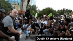 Полицейские встали на колено вместе с протестующими во время акции протеста из-за гибели после задержания полицией афроамериканца Джорджа Флойда, Атланта, 1 июня 2020 года.