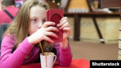 Чөнтөк телефонго алаксып отурган кыз.