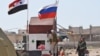 SYRIA -- A Russian soldier places the Russian national flag at the Abu Duhur crossing on the eastern edge of Idlib province, September 25, 2018