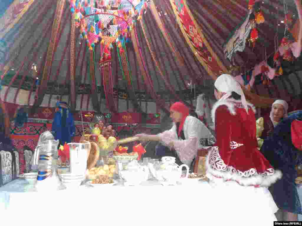 Девушки в национальном костюме накрывают дастархан.