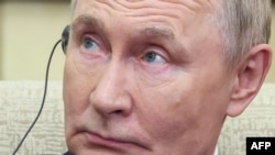 Russian President Vladimir Putin listens to a headphone translation in Beijing.