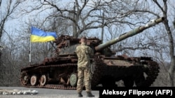 Weýran edilen rus tankynyň ýynda duran ukrain esgeri