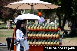 Людзі хаваюца ад пякучага сонца пад парасонам. Лісабон. Партугалія, 29 чэрвеня 2025 году