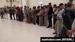 Aşgabadyň halkara aeroportunda uçar biledini satyn almak üçin nobata duran adamlar. Illýustrasiýa suraty