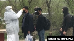 Тиббиёт ходими Чимкент шаҳрига кираётганларнинг тана ҳароратини текширмоқда.