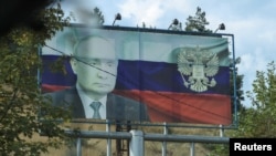 A board displaying a Russian state flag and an image of President Vladimir Putin is seen in Stepanakert, October 2, 2023.