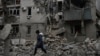 A woman walks past the debris of the destroyed house after a recent Russian air strike in Chasiv Yar on November 27. Shelling by Russian forces struck several areas in eastern and southern Ukraine as utility crews continued a scramble to restore power, water, and heating.