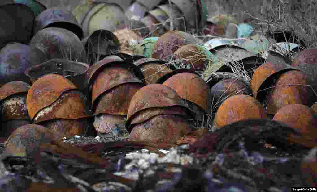 Іржаві пошкоджені армійські каски купою лежать на дорозі передмістя Степанакерта&nbsp;(Ханкенді)