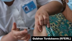 Дарыгер коронавируска каршы вакцинаны сайып жатат. Кыргызстан.