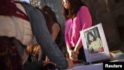 Люди, пришедшие отдать дань памяти жертв взрывов в Бостоне 15 апреля 2013 года,  оставляют свои соболезнования перед фотографией погибшей студентки Бостонского университета Лу Лингзи. 