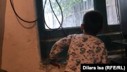 Жаңаауыл тұрғыны Мейірбек Өтегановтың кенже ұлы үйдің терезесінен сыртқа қарап тұр. Жетісай ауданы, Түркістан облысы, 30 қыркүйек 2020 жыл.