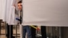 A young boy peeps out from behind the curtains of a voting booth at a polling station during the municipal elections in Moscow on September 10. 