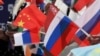 Spectators wave Russian, Chinese, and other flags during a June ceremony in central Moscow marking the 100-day countdown to the upcoming Intervision contest on September 20. 