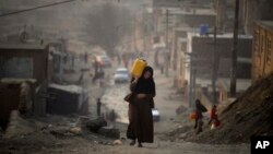 Kabildə qadın yamacla qalxaraq plastik qabda evinə su daşıyır.