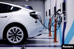 Қуат станциясында тұрған электр көлігі. Көрнекі сурет.