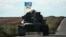 UKRAINE – A Ukrainian tank rides with a flag picturing Ukraine and US flags shaking hands in Novostepanivka, Kharkiv region, on September 19, 2022