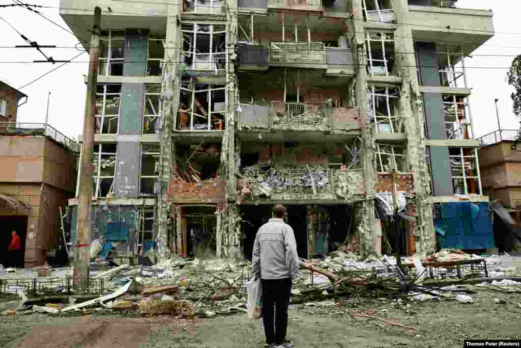 У Києві відомо про 11 постраждалих, пошкодження бізнес-центру і гуртожитку.На фото чоловік дивиться на будинок, пошкоджений внаслідок удару російського безпілотника на тлі масованого нападу Росії на Україну 25 травня 2025 року