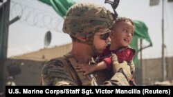 Бала көтөрүп турган америкалык аскер. 22-август,  2021-жыл. Кабулдагы Хамид Карзай атындагы аэропорт.  