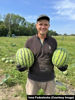 Чоловік Інни показує кавуни, які вони виростили на Івано-Франківщині
