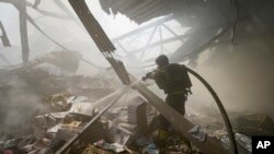 Рятувальник гасить пожежу після того, як російська ракета влучила у велику друкарню в Харкові, Україна, 23 травня 2024 року