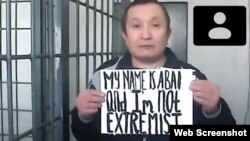 Соттағы жарыссөз кезінде ағылшынша "Есімім Абай және мен экстремист емеспін" деп жазылған қағаз ұстап тұрған белсенді Абай Бегімбетов. Алматы, 28 қыркүйек 2021 жыл.