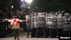 Пратэстоўца ў Тбілісі насупраць сьцяны паліцэйскіх шчытоў, 4 кастрычніка 2025 году