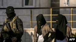 Сириядагы Камышлы шаарынын жанында жүзү толук чүмбөттөлгөн өзбек аялдары Өзбекстандын дипломаттарына өткөрүлүп берилип жаткан учур.   2019-жылдын 29-майы.