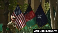 یک سرباز امریکایی در مقابل بیرق‌های امریکا، افغانستان، ناتو و حمایت قاطع.