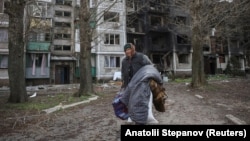 Жанчына нясе свае рэчы, каб эвакуавацца з Пакроўску Данецкай вобласьці. 12 красавіка 2025 году