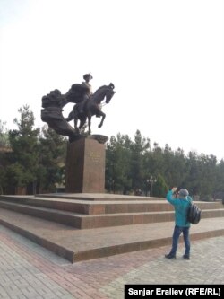 Кыргызстандык турист Анжияндагы Бабурдун айкелин сүрөткө тартып жатат.