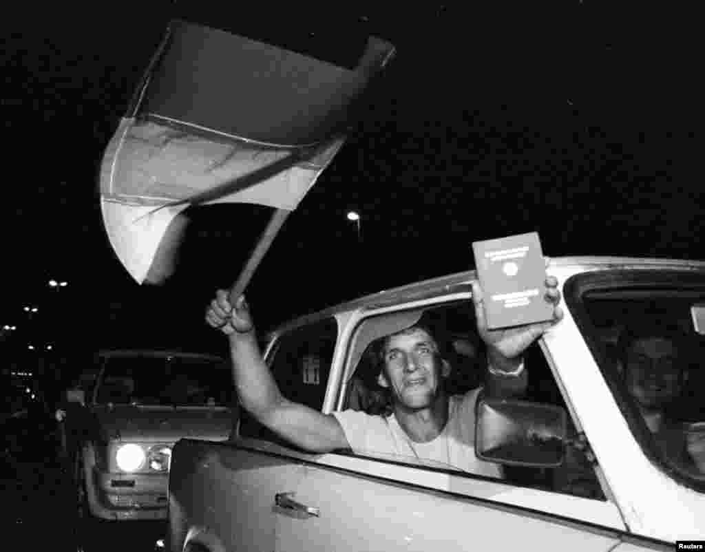 An East German shows off a newly acquired West German passport just before crossing into Austria overnight on September 10-11.