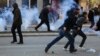 Protesters run away from tear gas fired by police officers during clashes at the Pristina on February 7.