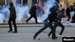 Protesters run away from tear gas fired by police officers during clashes at the Pristina on February 7.