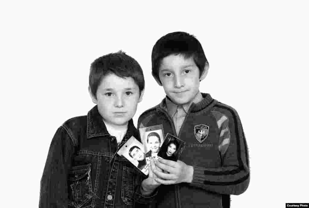 Братья Тимур и Хетаг Тамаевы с портретами убитых отца, матери и брата - Эти два брата – круглые сироты. Погибли все родные – отец, мать и старший брат. Тяжелее всего, что Тимур и Хетаг их не помнят – были еще слишком малы, поэтому-то супруги Артур и Инга оставили их дома, на попечении родных. А сами из школы, куда повели своего первенца Тотраза – в первый раз в первый класс – уже не вернулись. Мама Тимура и Хетага не дожила всего несколько месяцев до своего тридцатилетия. Закончила Инга ту же самую школу – номер один в Беслане. По окончании школы закончила курсы кройки и шитья и устроилась швеей в частное ателье в селении Чикола. Уже через год там же вышла замуж за Артура, а через год молодая семья перебралась в Беслан. Через год у них появился Тотраз, через пару лет – Хетаг и в январе 2001 – Тимур. Так как денег не хватало, Инга устроила сыновей в детский сад-ясли, а сама вышла на работу. А потом наступило 1 сентября 2004 года. Артура убили в первый же день. Инга и Тотраз погибли в п