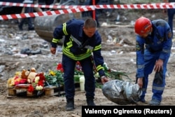 Ратавальнікі нясуць частку расійскай крылатай ракеты «Іскандэр-К», якая патрапіла ў жылы дом у Кіеве 1 жніўня 2025 года. REUTERS/Валянцін Агірэнка