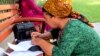 Turkmenistan. weekly photos 37th week. women are writing formal letter and sitting on bank