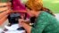 Turkmenistan. weekly photos 37th week. women are writing formal letter and sitting on bank